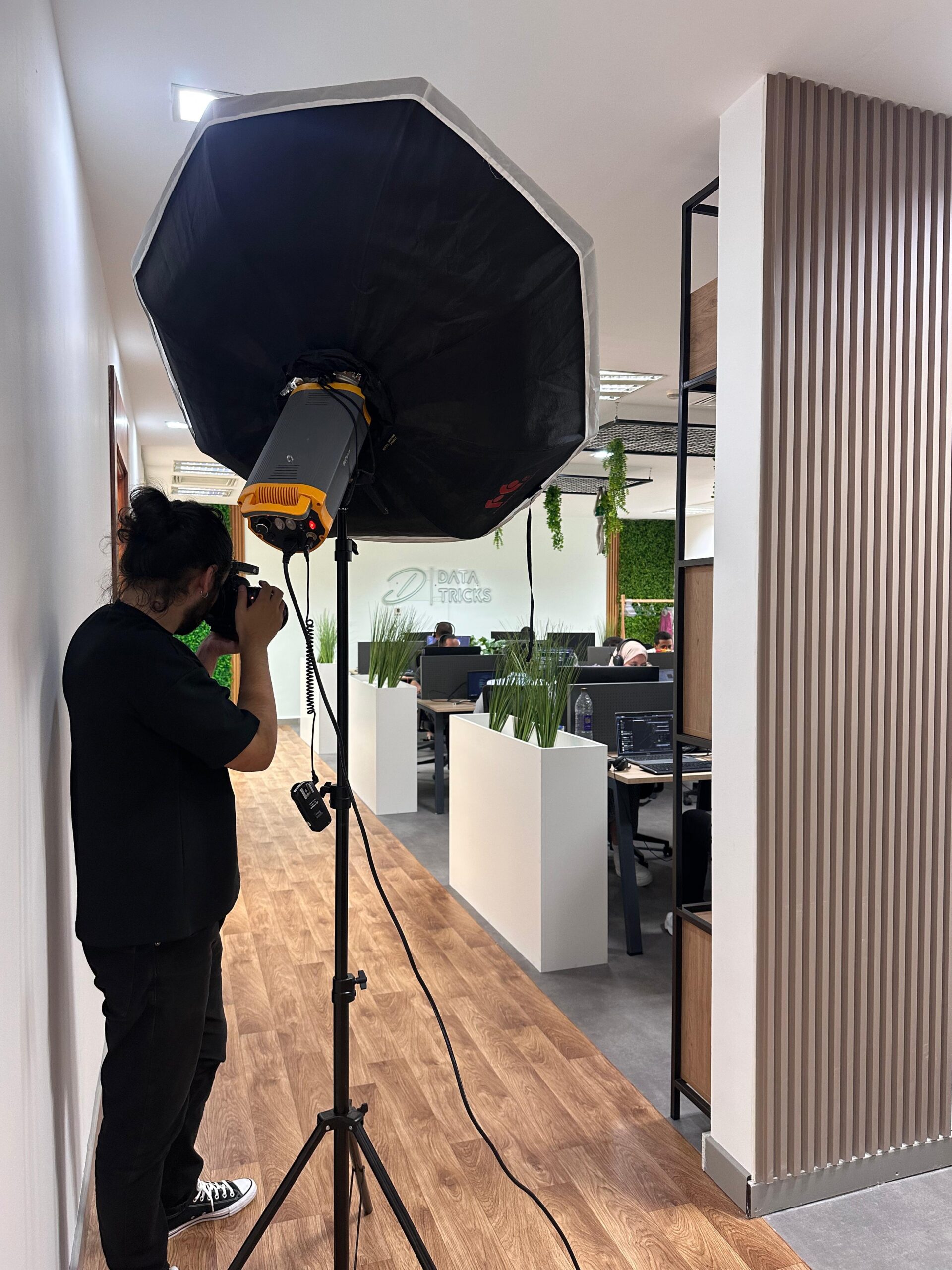 Behind the scenes: the photographer shooting with an octagonal softbox in a Data Tricks office corridor